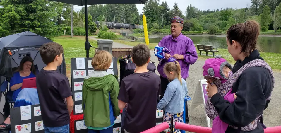 A balloon artist with kids at a park event