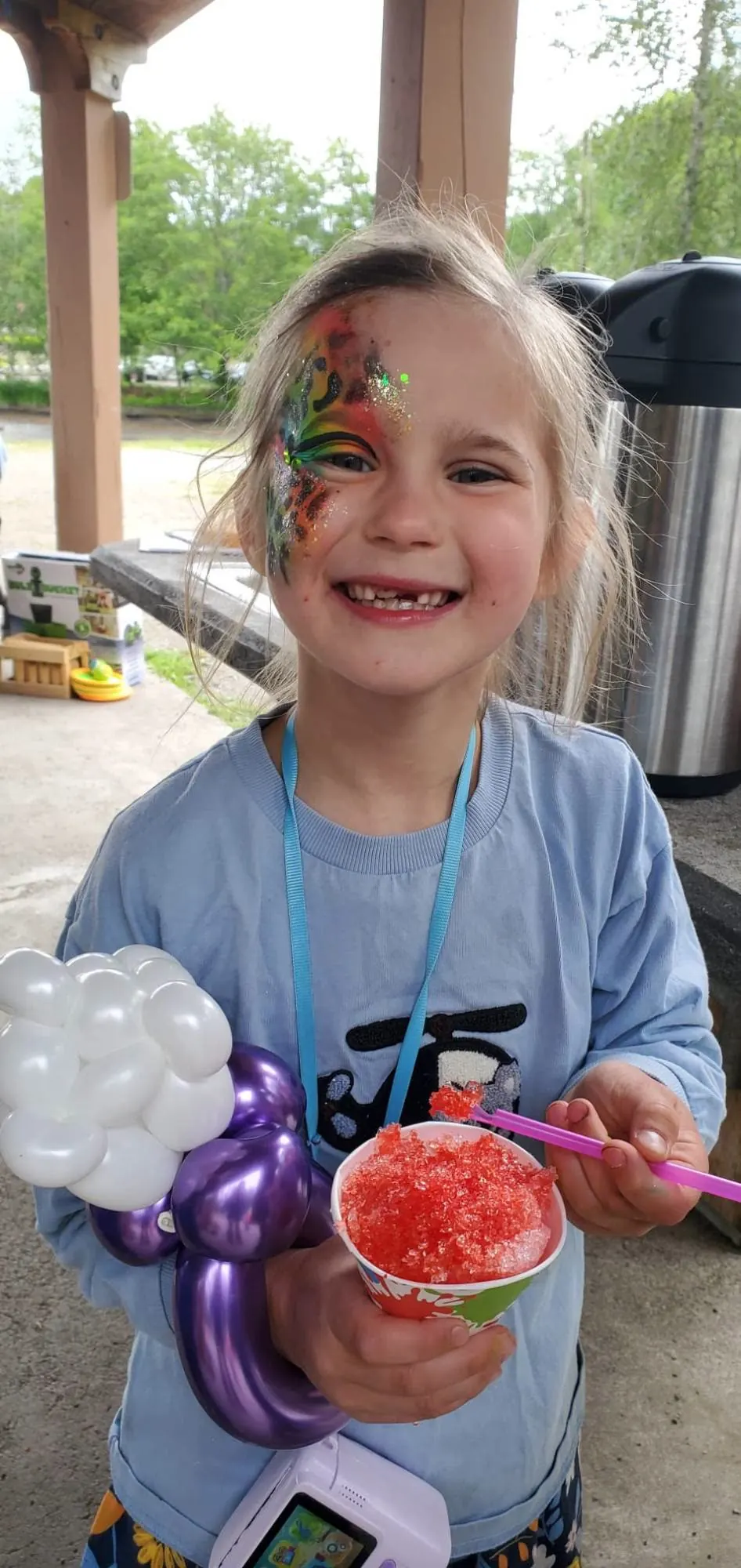 A girl with face paint holding a snow cone