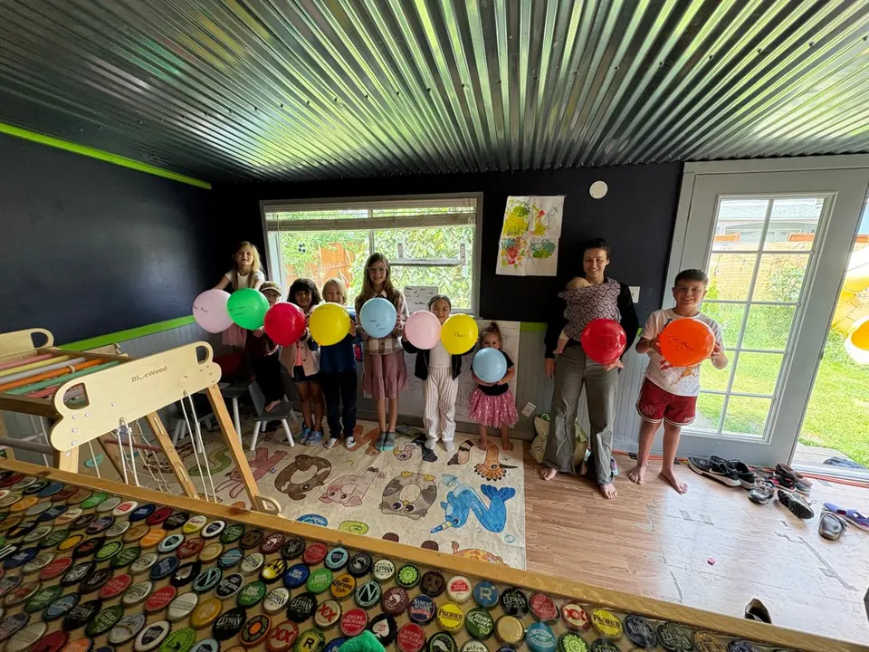 Kids holding balloons that spell out 1 Corinthians 12:27