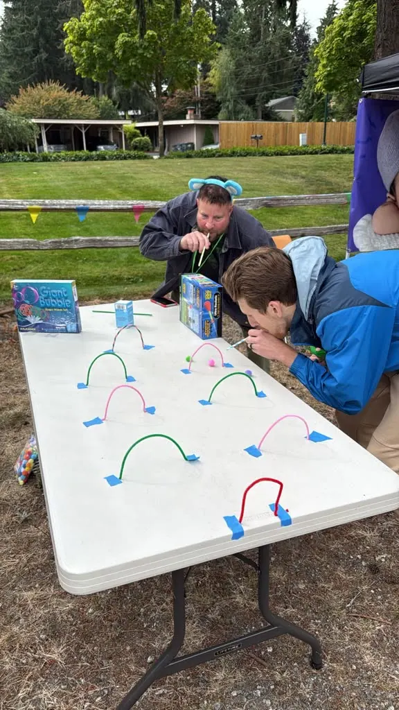 Two neighbors playing a straw blowing game at a park event